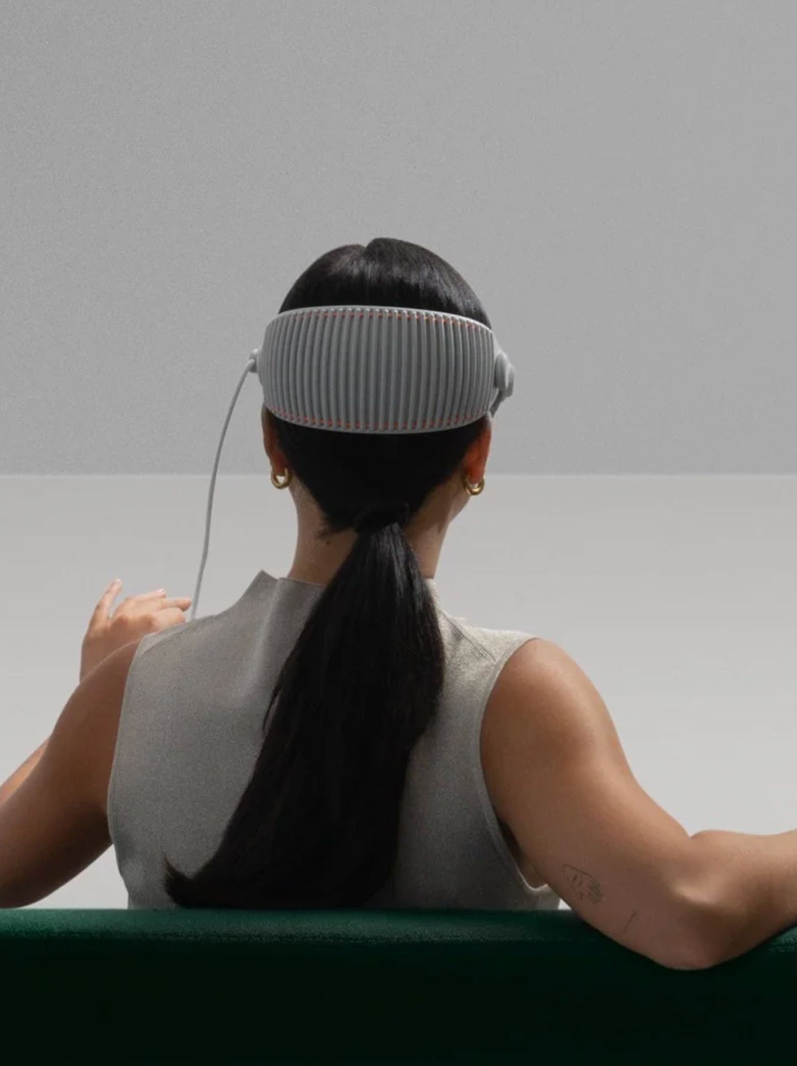 A woman wears a set of VR glasses. She is sitting, we see her from the back.