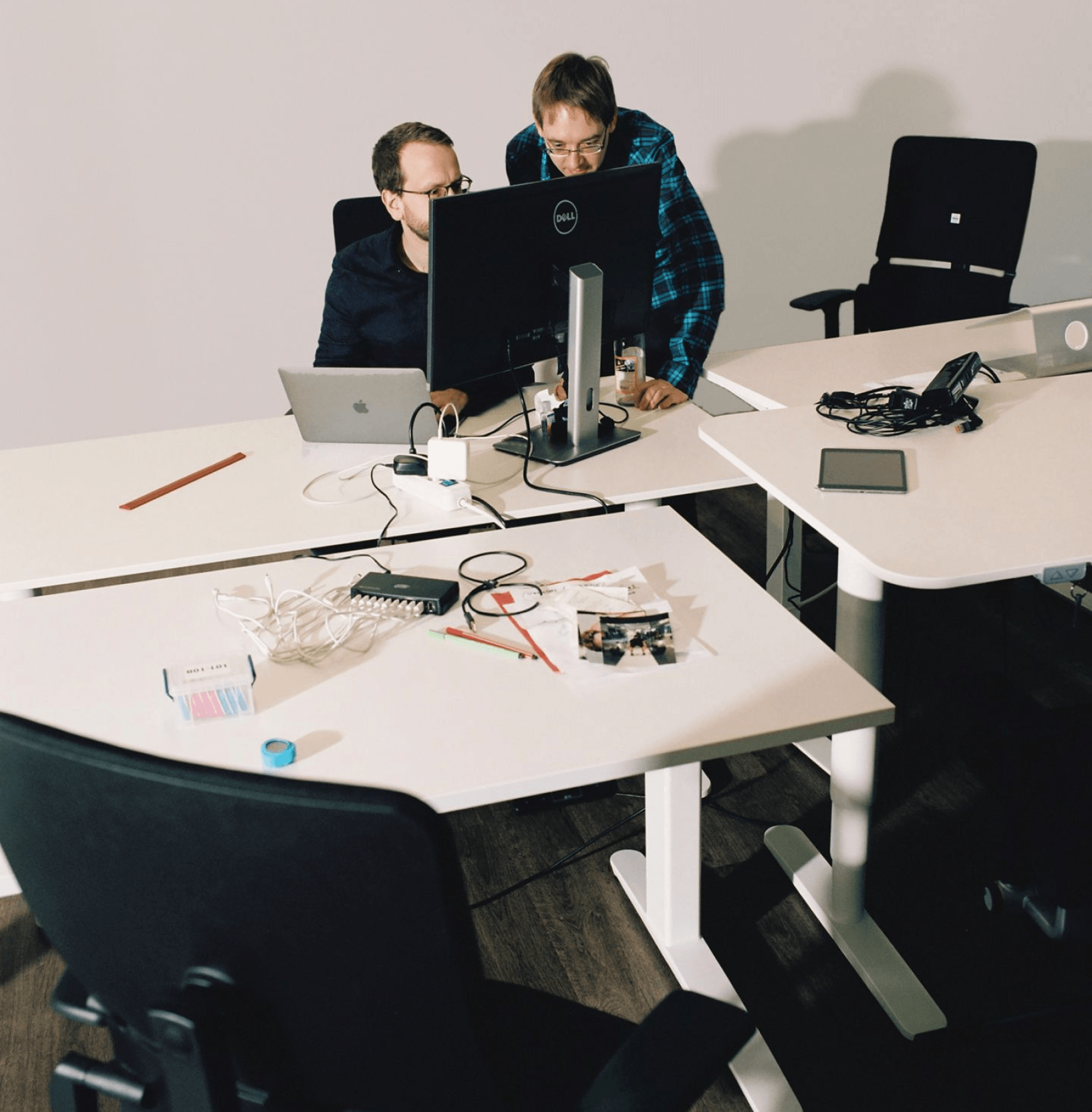 Two people pair-programming behind a computer display on a messy desk