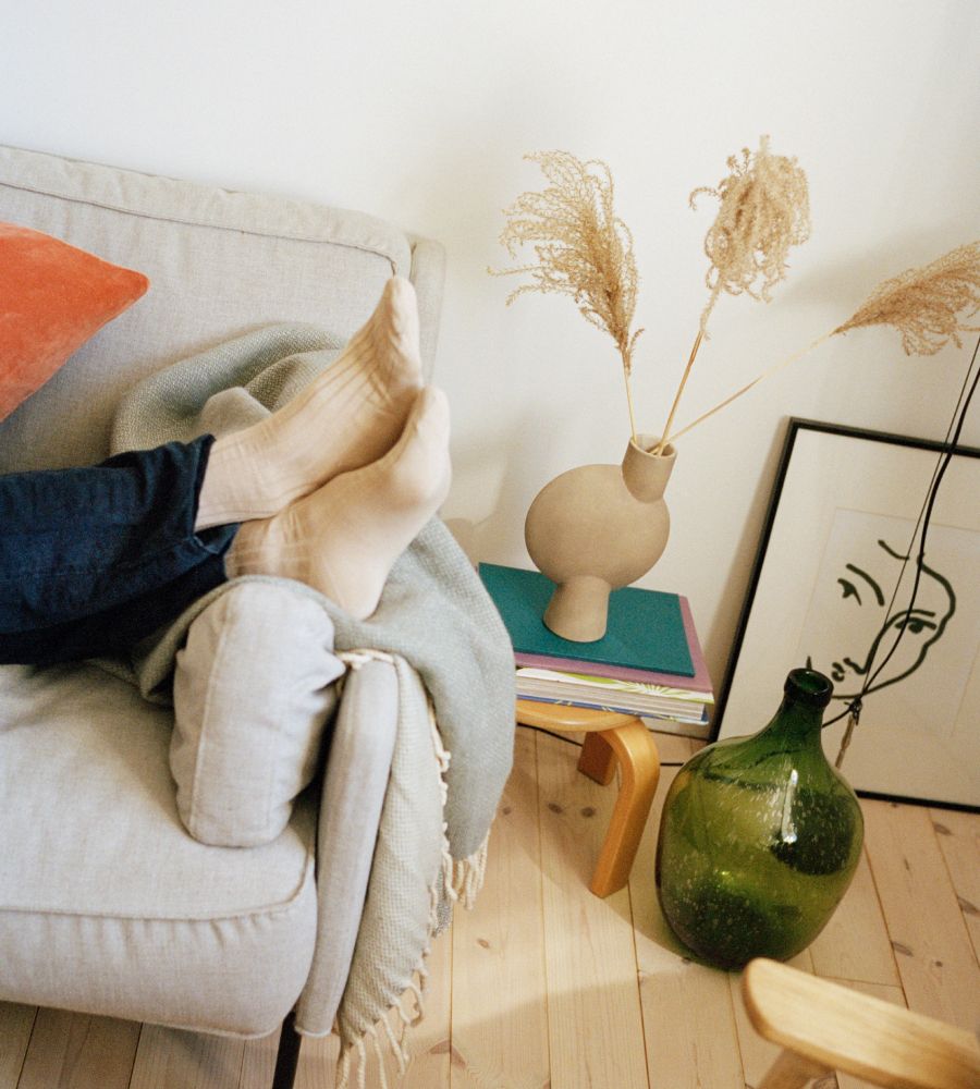 Closeup of someone with their feet on the side of a couch while wearing socks
