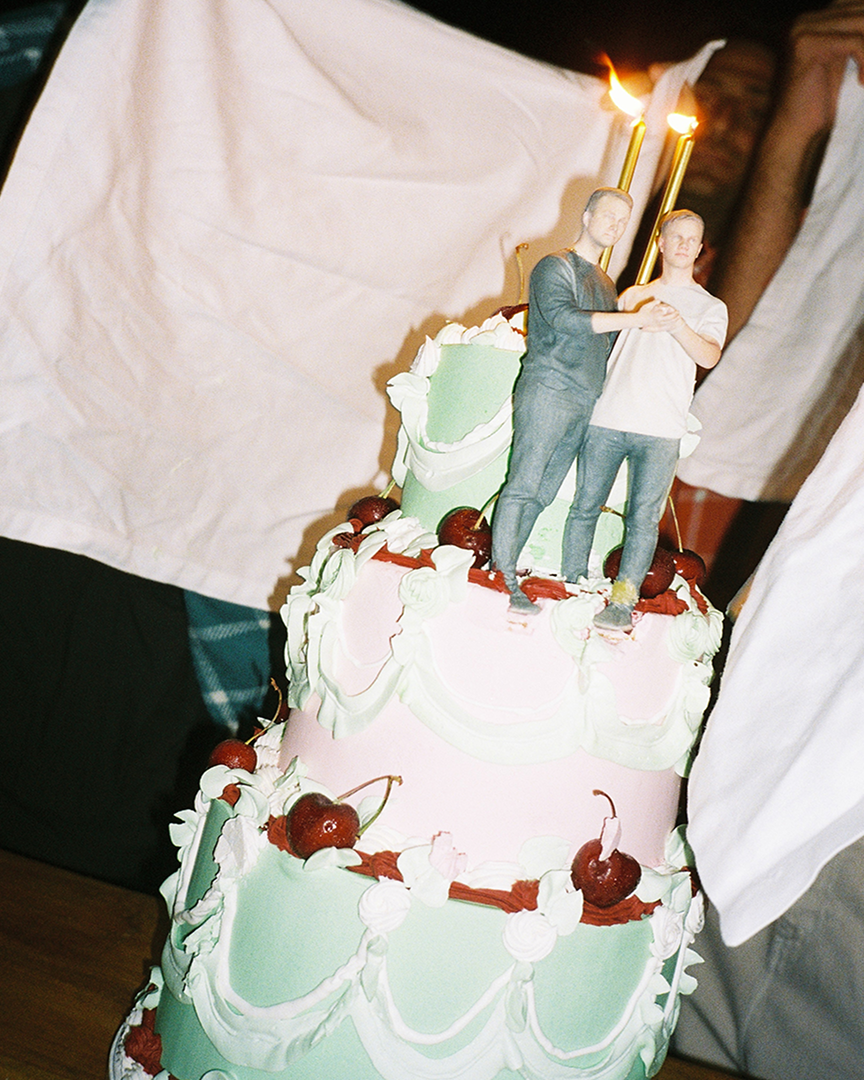 A wedding cake with a statue of two men. Night flash photography.